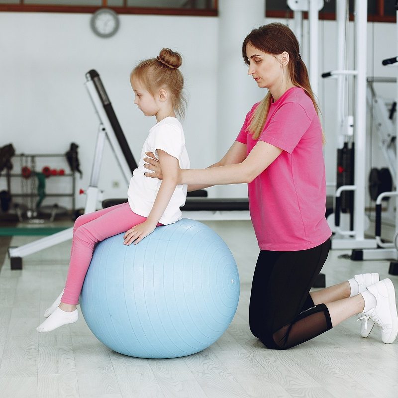 Mother with daughter in a gym. Little girl are engaged in gymnastics
